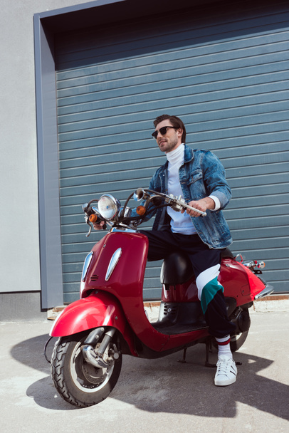 stylish young man in denim jacket on vintage red scooter - Photo, Image