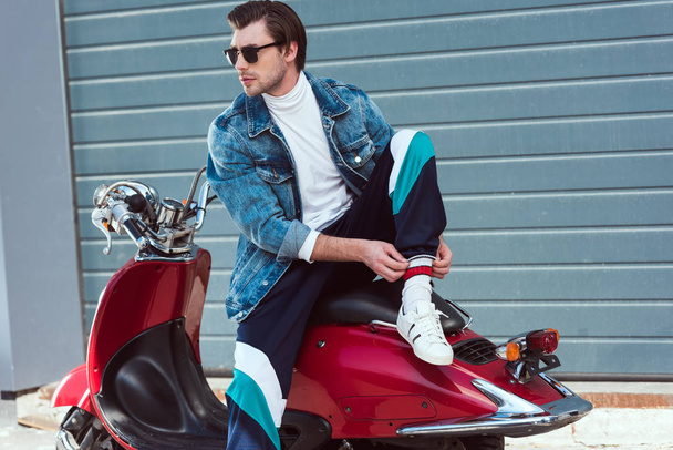handsome young man in stylish clothes sitting on vintage red scooter - Photo, Image