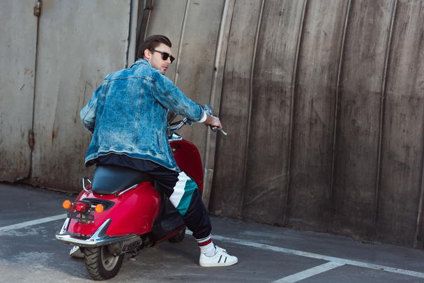 young man in stylish denim jacket with vintage scooter on parking - Fotografie, Obrázek