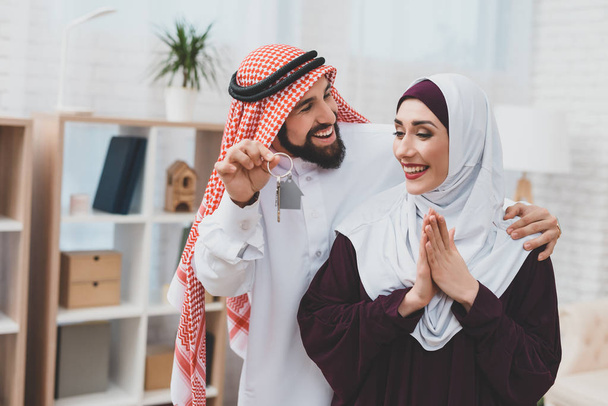 Arab man in kufiya making surprise to woman in hijab and presenting keys from apartment   - Φωτογραφία, εικόνα