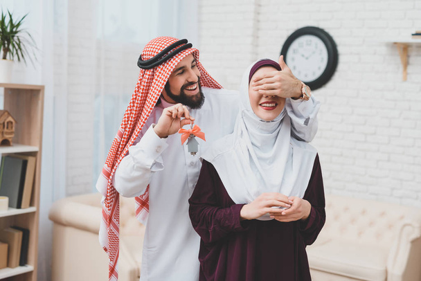 Arab man in kufiya making surprise to woman in hijab and presenting keys from apartment   - Фото, зображення