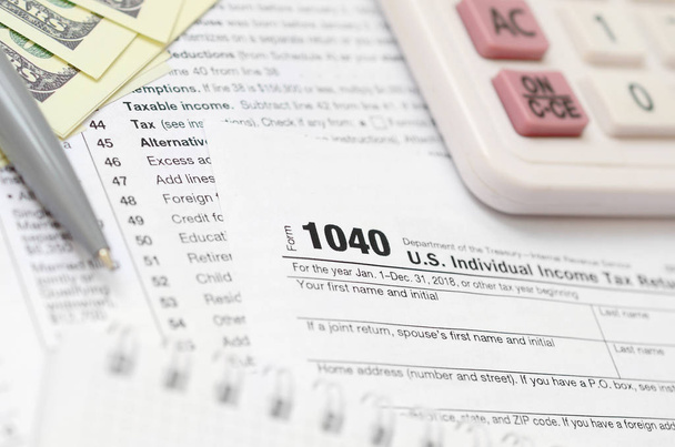 The pen, notebook, calculator, and dollar bills is lies on the tax form 1040 U.S. Individual Income Tax Return. The time to pay taxes - Photo, Image