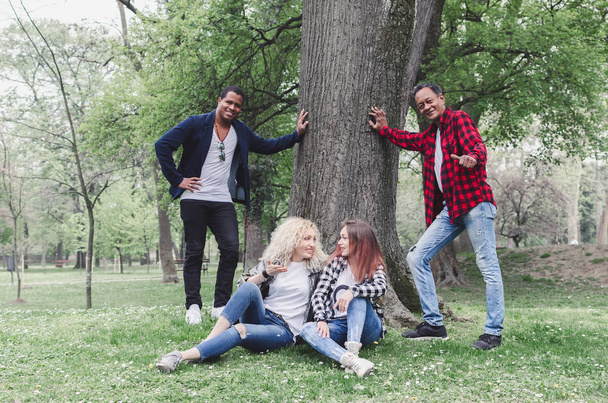 Group of friends relaxing in city park on grass - Foto, Bild