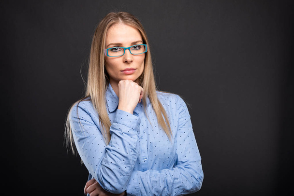 Business lady wearing blue glasses posing with hand on chi - Foto, immagini