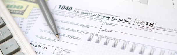 El bolígrafo, cuaderno, calculadora, y billetes de dólar es mentiras en el formulario de impuestos 1040 EE.UU. Declaración individual del impuesto sobre la renta. El momento de pagar impuestos
 - Foto, imagen