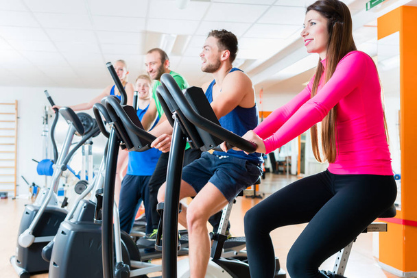 Men and women on cardio bikes in gym  - Photo, Image