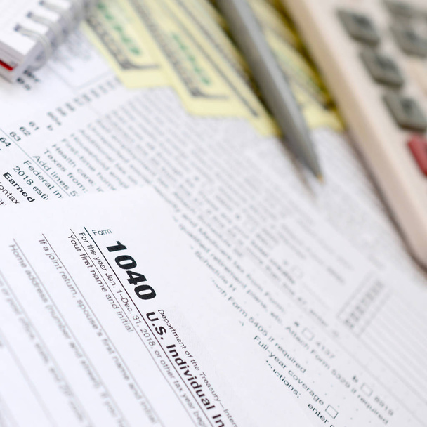 Długopis, Notatnik, kalkulator i Dolar rachunki jest, leży na podatek formularza 1040 indywidualnego podatku dochodowego Stanów Zjednoczonych. Czas, aby płacić podatki - Zdjęcie, obraz