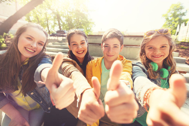 teenage friends or students showing thumbs up - Fotó, kép