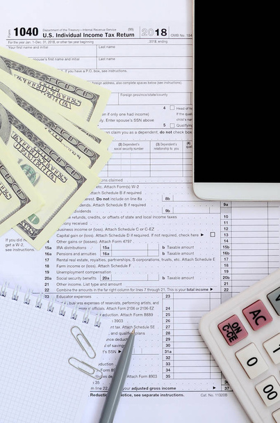 Σύνθεση των ειδών που βρίσκεται στο έντυπο 1040 φόρου. Λογαριασμούς δολαρίων, στυλό, Αριθμομηχανή, smartphone, συνδετήρα και Σημειωματάριο (Notepad). Η ώρα να πληρώνουν φόρους - Φωτογραφία, εικόνα
