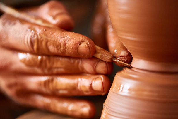 Close-up hands of a male potter in apron making a vase from clay, selective focus - Φωτογραφία, εικόνα
