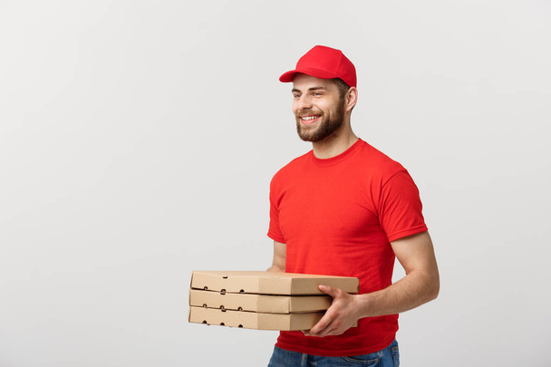Lieferkonzept: junger kaukasischer Pizzabote mit Pizzakartons vor grauem Hintergrund - Foto, Bild