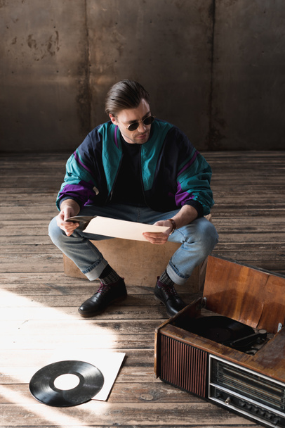 handsome young man in vintage windcheater with vinyl record player - Фото, зображення