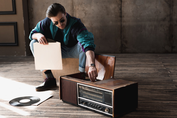 handsome nostalgic man in vintage windcheater with vinyl record player - Photo, Image