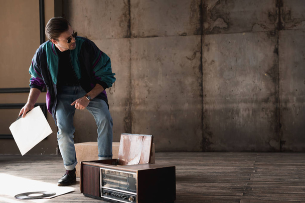 stylish young man in vintage windcheater with vinyl record player - Photo, Image