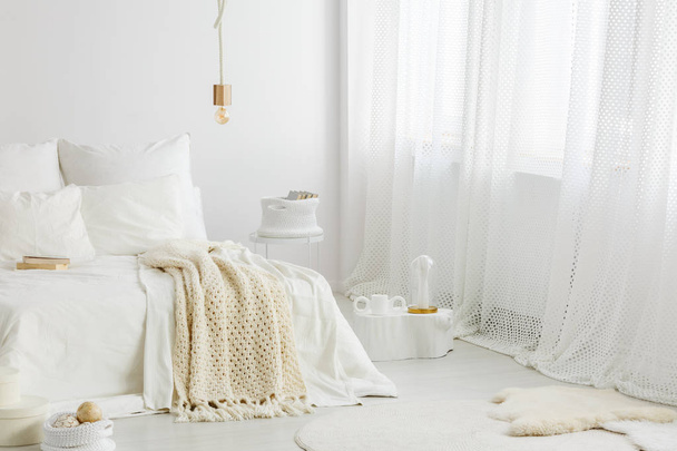 居心地の良い、窓が大きくて明るい寝室のインテリアで白いベッドの上の毛布をニット - 写真・画像