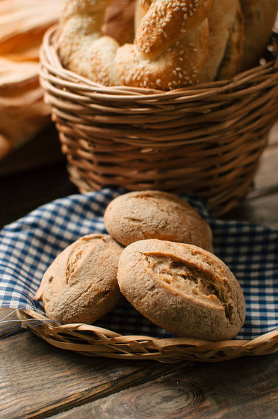 Pyszne, świeżo pieczone bochenków chleba w wiklinowym koszu na drewnianym stole - Zdjęcie, obraz