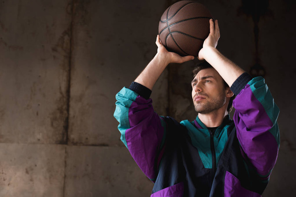 handsome young man in vintage windcheater throwing basketball ball - Фото, изображение