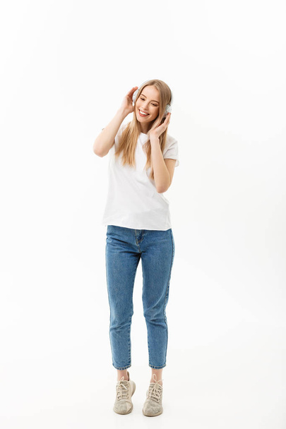 Lifestyle Concept: Portrait of a cheerful happy girl student listening to music with headphones while dancing isolated over white background - Fotografie, Obrázek