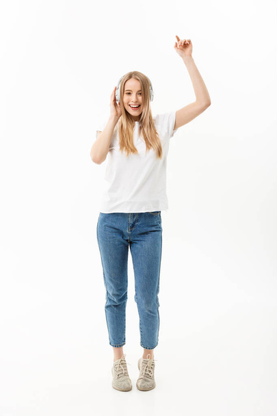 Lifestyle Concept: Portrait of a cheerful happy girl student listening to music with headphones while dancing isolated over white background - Foto, Bild