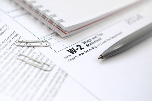Ручка и тетрадь на бланке налогообложения W-2 Wage and Tax Statement. Время платить налоги
 - Фото, изображение