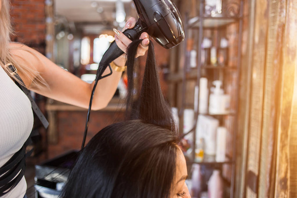 Female hairdresser making hairstyle to girl in beauty salon. - Fotó, kép