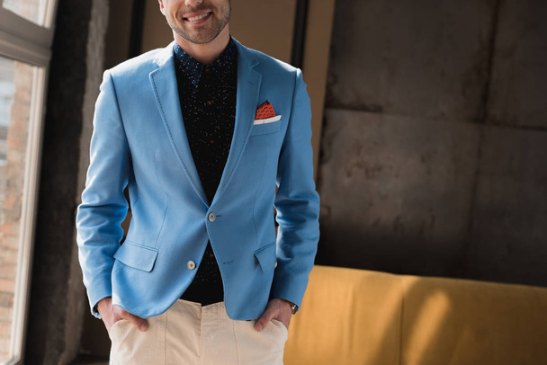 cropped shot of smiling young man in stylish blue jacket in loft interior - Fotoğraf, Görsel