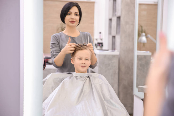 Professional female hairdresser working with little boy in salon - Fotó, kép