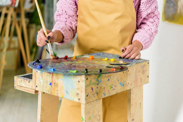 cropped image of female artist applying paints on palette in workshop - Fotoğraf, Görsel