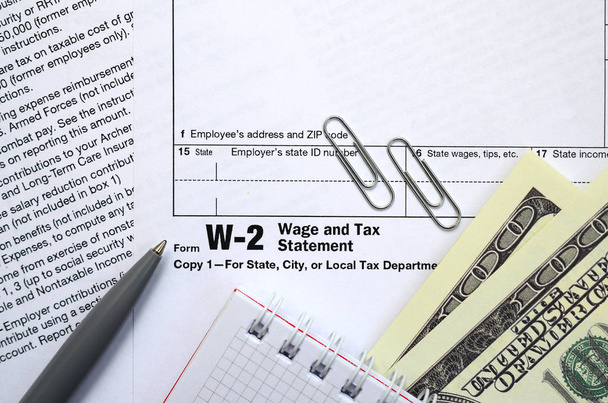 Το στυλό, σημειωματάριο και Δολάριο γραμμάτια βρίσκεται στο φορολογικό έντυπο w-2 μισθολογική και φορολογική δήλωση. Η ώρα να πληρώνουν φόρους - Φωτογραφία, εικόνα