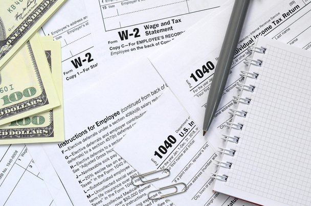 El bolígrafo, cuaderno y billetes de dólar se encuentra en el formulario de impuestos 1040 EE.UU. Declaración individual del impuesto sobre la renta. El momento de pagar impuestos
 - Foto, imagen