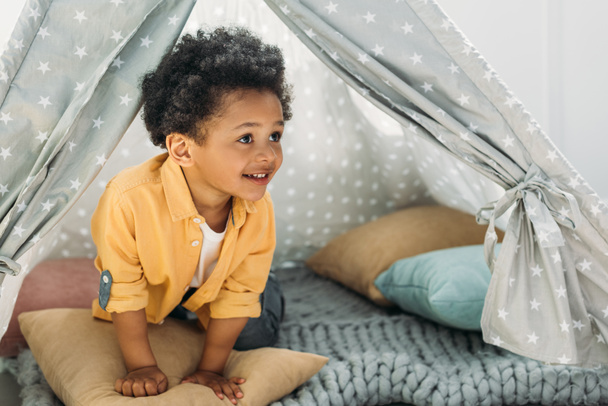 little smiling african american boy in teepee at home - Foto, afbeelding