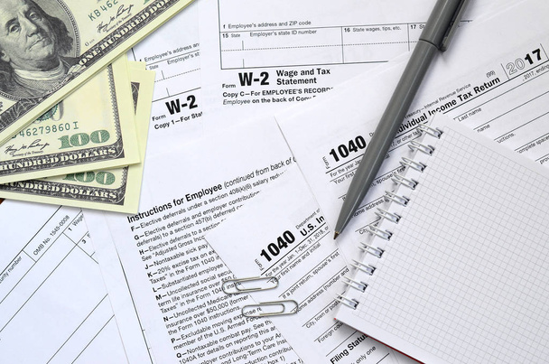Le stylo, bloc-notes et billets en dollars se trouve sur le formulaire d'impôt 1040 États-Unis Déclaration de revenus des particuliers. Le temps de payer les impôts
 - Photo, image