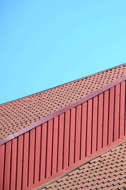 Een fragment van een dak van een metalen tegel van donker rode kleur. Kwaliteit dakbedekking - Foto, afbeelding