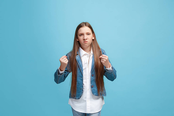 Portrait of angry teen girl on a blue studio background - Zdjęcie, obraz