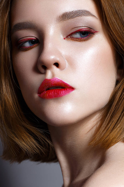 Young girl with red lips and red arrows in front of eyes. Beautiful model with makeup nude and shining skin. Photo taken in the studio. Beauty of the face. Female portrait.  - Foto, Imagem