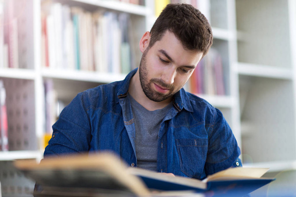 Young male student studying in the library - Fotoğraf, Görsel