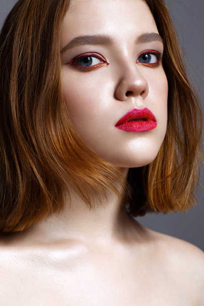 Young girl with red lips and red arrows in front of eyes. Beautiful model with makeup nude and shining skin. Photo taken in the studio. Beauty of the face. Female portrait.  - Foto, Imagem