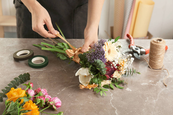 Female florist making beautiful bouquet at table - Fotó, kép