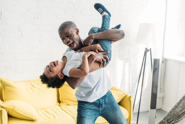 happy african american man playing together with little son at home - Photo, Image