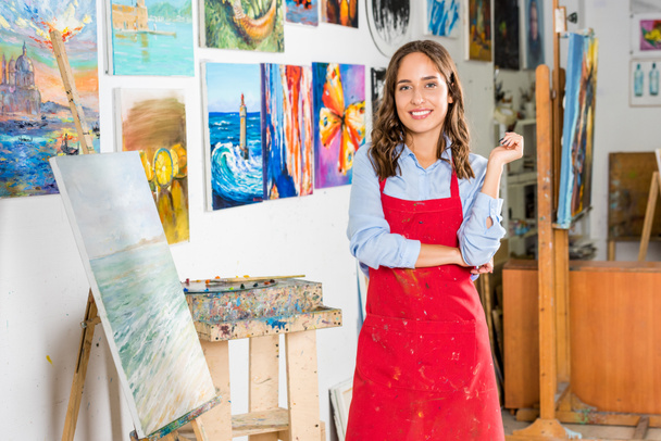 beautiful female artist standing and looking at camera in workshop - Foto, Imagen