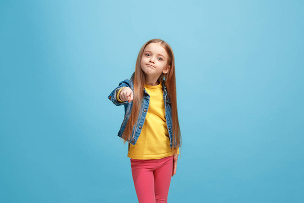 The happy teen girl pointing to you, half length closeup portrait on blue background. - Foto, immagini