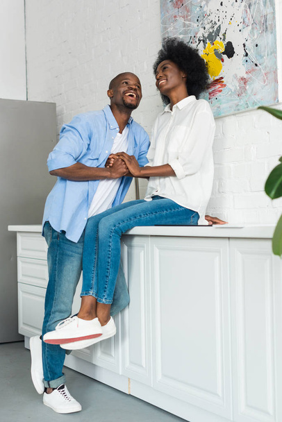 happy african american couple holding hands in kitchen at home - Foto, Bild
