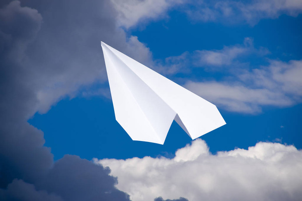 White paper airplane in a blue sky with clouds. The message symbol in the messenger - Zdjęcie, obraz