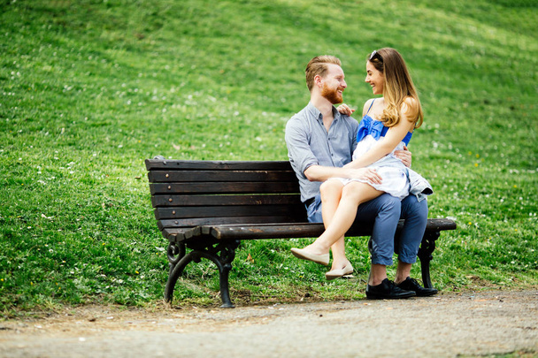 Romantic couple in park sitting on bench - Φωτογραφία, εικόνα