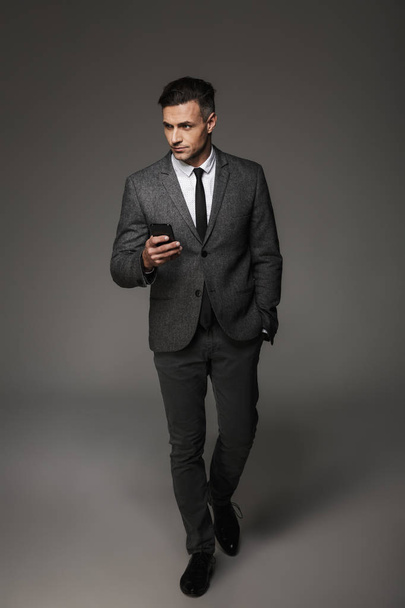 Full-length image of young unshaved man 30s wearing suit and tie - Foto, imagen