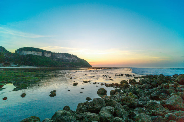 Plaża skały zielony w Bali, Indonesia.Sunrise Bali Beach z skały Zielone wodorosty na plaży. - Zdjęcie, obraz