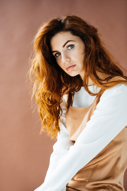 Attractive redhead woman looking at camera isolated on brown background - Fotoğraf, Görsel
