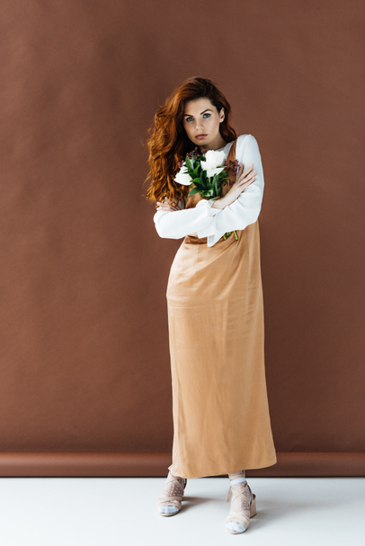 Woman with long red hair holding bouquet of flowers - Foto, imagen