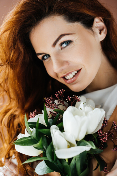 Beautiful young girl with bouquet of flowers isolated on brown background - Foto, Imagem