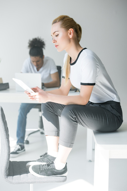 attraktive junge Frau sitzt am Tisch und nutzt digitales Tablet im Büro - Foto, Bild